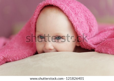 Picture of a baby lying under towel in bed