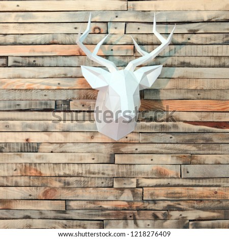 Paper deer head on the wall of wooden bars. Designer background for decoration in the room. New Year's wall decoration. Square picture.