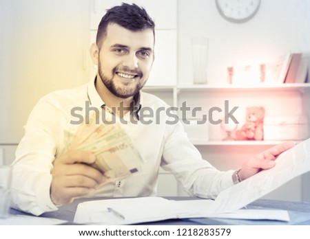 Young happy cheerful positive man struggling to pay utility bills and rent for his apartment