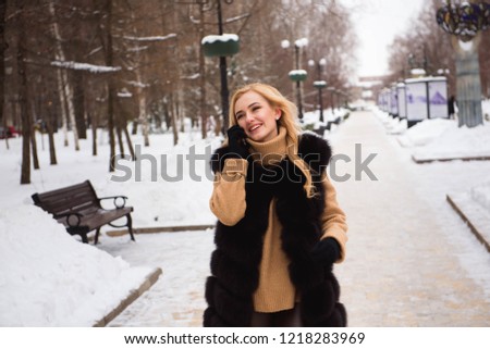 Outdoor close up photo of young beautiful happy smiling girl walking on street in winter.
