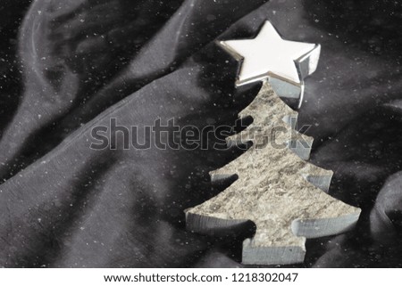 Christmas decorations stone tree and star on the black silk background.Snow textured