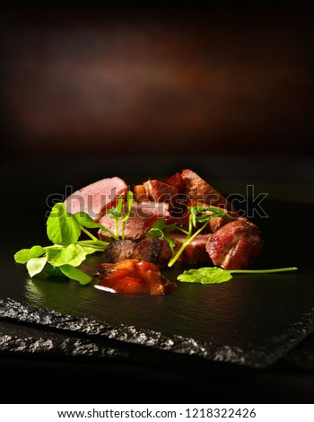 Sliced roasted wild duck breasts with fresh watercress and Lambs lettuce salad shot against a rustic background with accommodation for copy space.