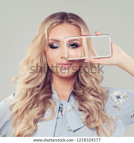 Beautiful blonde woman using smartphone. Girl showing selfie photo on cell phone