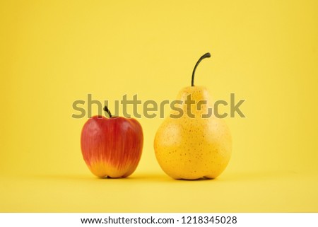 Pear and apple decoration stock images. Yellow pear and red apple on a yellow background. Fruit home decor. Plastic decorative fruit