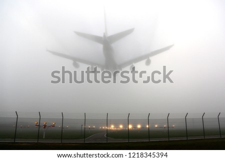 Civil wide-body airliner landing in fog. Royalty-Free Stock Photo #1218345394