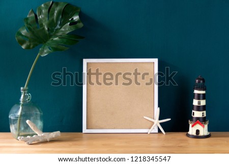 Workspace decoration with white photo frame and tropical monstera leaf in sea set design