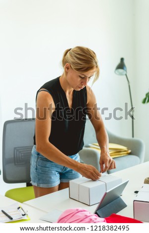 Young entrepreneur packing a package for sending