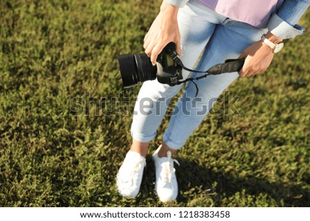 Young female photographer holding professional camera outdoors. Space for text