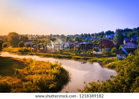 The river flows through the village Russia in sunset time.