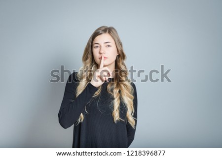 beautiful blond woman shows sign of quiet, secret, isolated over gray background