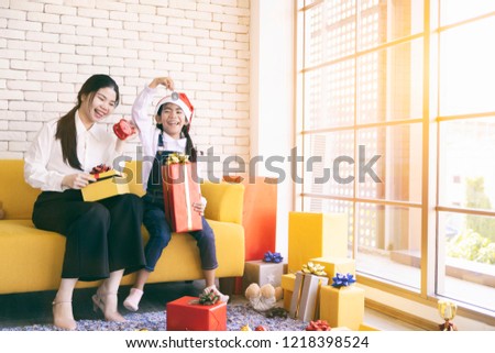 Happy mother and daughter in the family Christmas tree with presents.