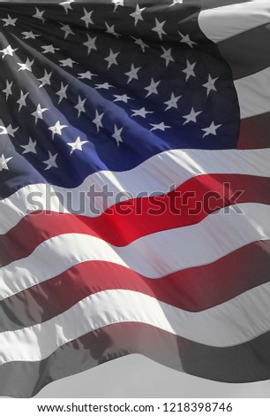 Close up isolated vertical colorful waving rippled United states of American U.S. flag with stars and stripes red white and blue part fading to gray