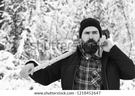 lumberjack concept. lumberjack man working in the winter forest. Guy with thoughtful face with forest covered by snow on background. Hipster woodsman concept. Man in hat with beard and mustache holds