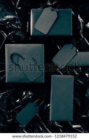 flat lay with black boxes with blank price tags on black wrapping paper backdrop, black friday concept