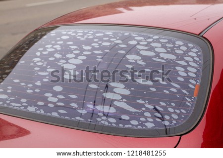 The rear window of a car with a very poor substandard tint. Defective rear window tinted red car. Bubbles when tinting auto glass. The poor work of the car tinting master. Bubbles on glass. Royalty-Free Stock Photo #1218481255