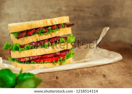 Sandwiches - bread, meat, basil, fresh leaves of lettuce on a wooden background. top view. copy space
