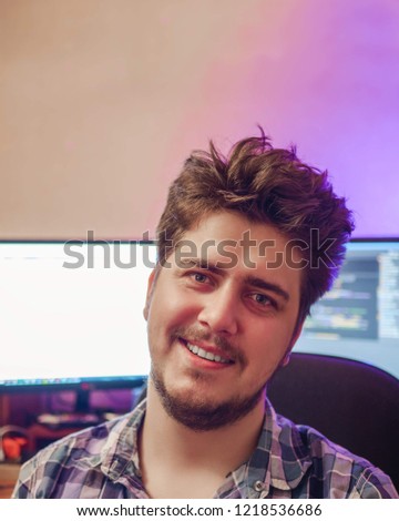 Portrait of smiling man with computer with two screen and pink and orange light on background. Spring day. Copy space for text.