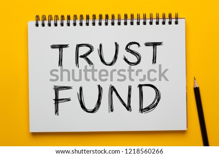 TRUST FUND written on notepad with pencil on yellow background. Business concept.