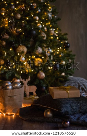 winter decor: Christmas tree,garland, balls, gifts and cozy striped and gray plaids with pillows on wooden background. Selected focus