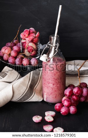 Still life. Fresh red grapes and a bottle of juice smoothies from grapes on a dark background. Healthy food.