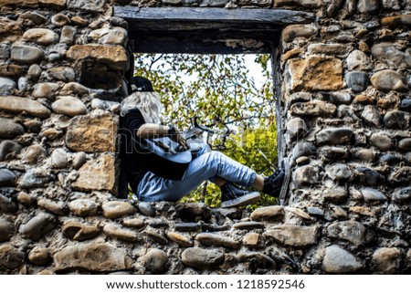Guitarist girl.  
Girl sitting on the ruins window plays a guitar.