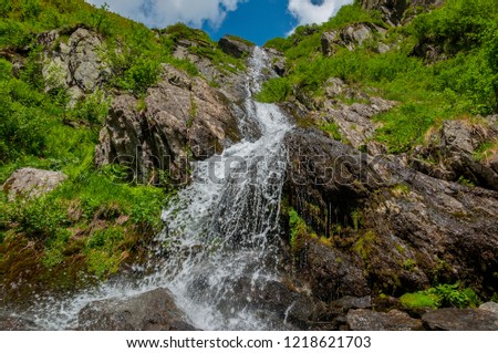 Close up mountain waterfall in Carpathians mountains. Sitting on the rock edge near faterfall and enjoying stunning  view.