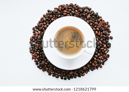 Cup of coffee close up with coffee beans on white isolated background, top view with free space for text