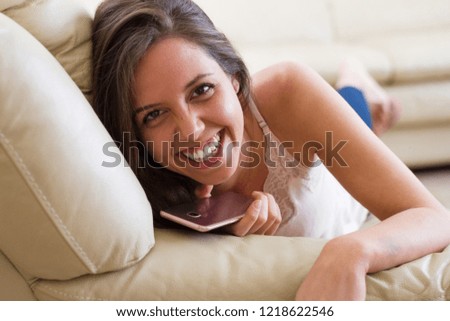 Perfect smile Pretty young brunette girl resting on the couch while taking mobile and smiling in front of the camera, happy and happy
