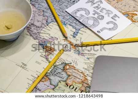World traveler trying to decide where to go next. Playing with a map with the travel bug trying to figure out the next destination. Playful tabletop travel images. 
