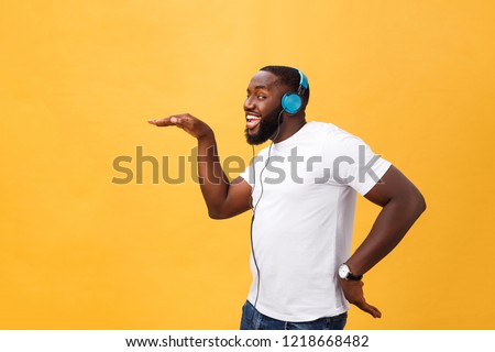 Young African American man wearing headphone and enjoy music dancing over yellow gold Background