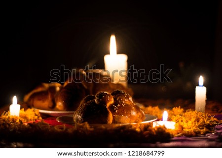 bread of dead on chopped paper and lighted candles and petals of cempasuchil with dark background
