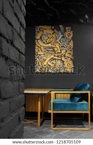 Modern lounge bar interior. Golden radiator and picture abstract on the wall. Dark cyan chairs.