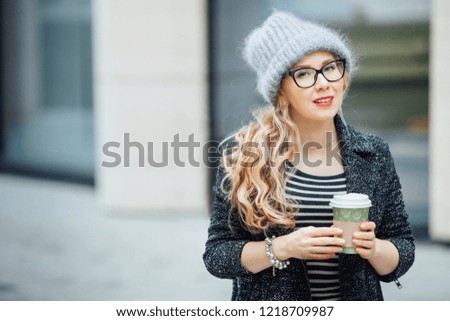 The girl with glasses drinks coffee in cold weather