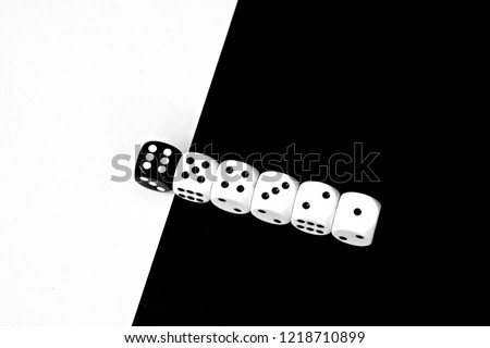 Game cubes are next to each other. Five white dice range from one to five in a row on a black background, the sixth dice is black on a white background - concept with contrast and dice