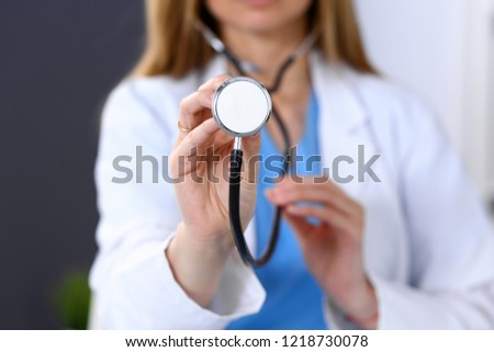 Doctor holds stethoscope head, close-up. Medical help and insurance in health care, best treatment and medicine concept. Blue tone of picture