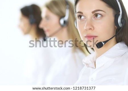 Group of call center operators at work. Focus at beautiful business woman in headset