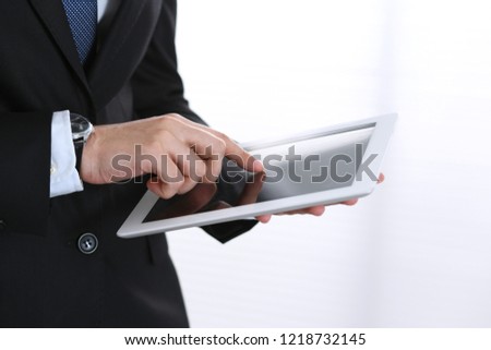 Unknown businessman holding digital tablet in office