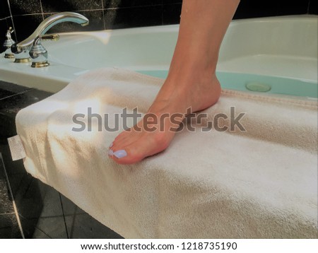 Photo of woman feet stepping on a white towel after bath