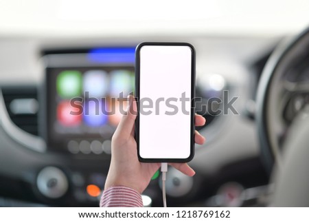 Cropped shot of female hand holding mobile phone in car.