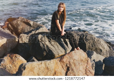 young and beautiful girl sitting by the the autumn cold sea
