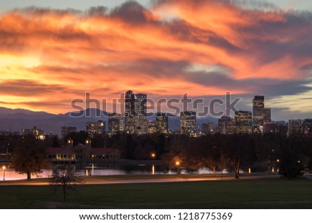 Denver Colorado skyline during sunset, with the Rocky Mountains visible in the background. 