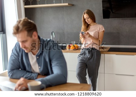 awesome fair-haired housewife sending SMS while her friend using the notebook. blurred foreground. secret message from paramour Royalty-Free Stock Photo #1218809620