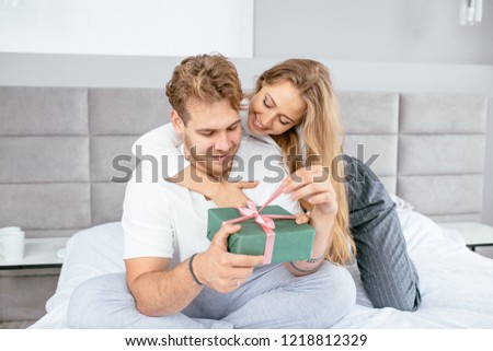 beautiful wife helping to open the gift box to her handsome happy husband. close up photo. holidays, christmas, valentine's day, Father's day