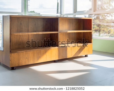 Empty wooden book shelf near window glass with light and shadow on sunny day in cafe with space.