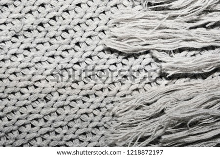 The texture of the knitted gray fabric with a fringe of threads for the background