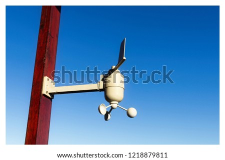 A weather measuring device attached to a wooden pole with a blue sky background. This image can use to represent the concept of meteorology or weather forecasting. 