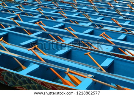 Neatly arranged blue boats and paddles.