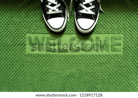 Black sneakers shoe on fabric green welcome mat ,top view for copy space