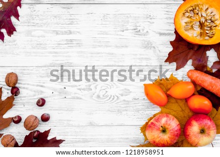 Autumn nature concept. Background with autumn symbols. Brown leaves, apple, tomatoes, pumpkin, carrot on white wooden background top view space for text