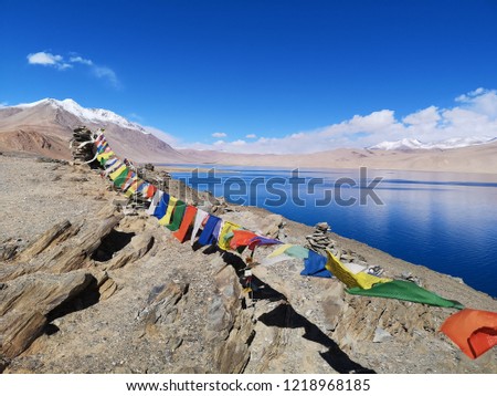 View of lake and  colorful praying flags in Leh Ladakh India with hill and blue sky in the background.